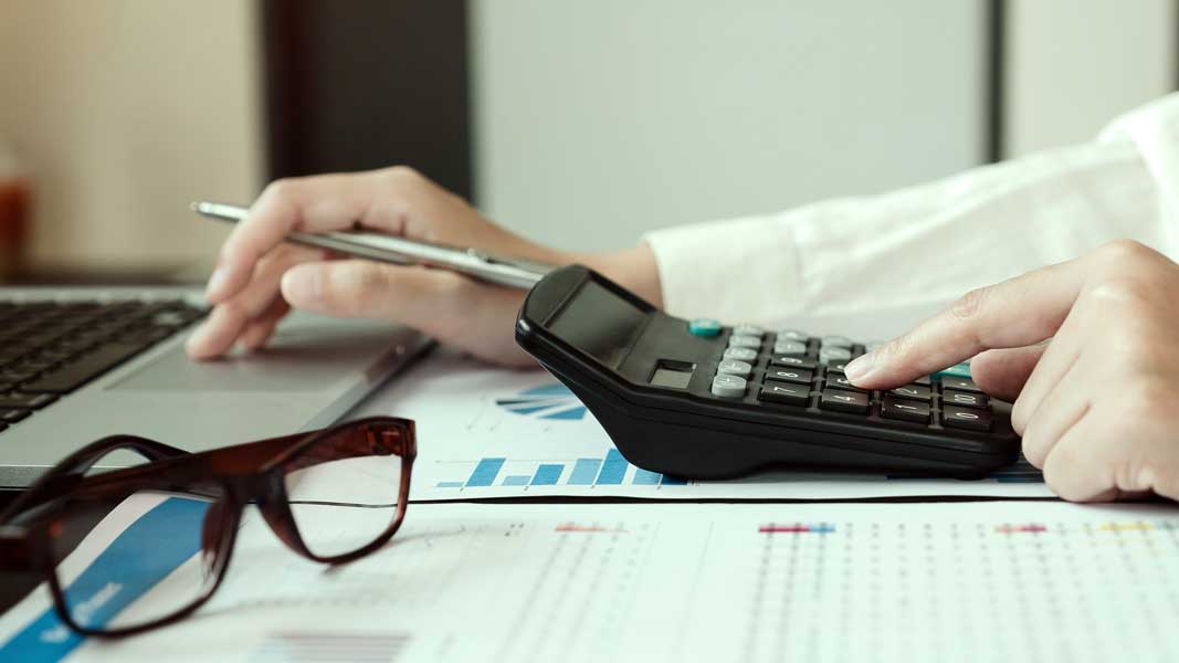 Business woman using calculator and laptop for do math finance o Manually calculating Debt Service Ratio