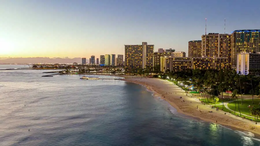 Photo of a Lit City Skyline at Dusk by the Ocean with Sandy Beach Front